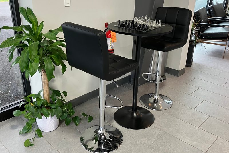 A chess table and black lounge chairs beside the Levant Motors showroom windows