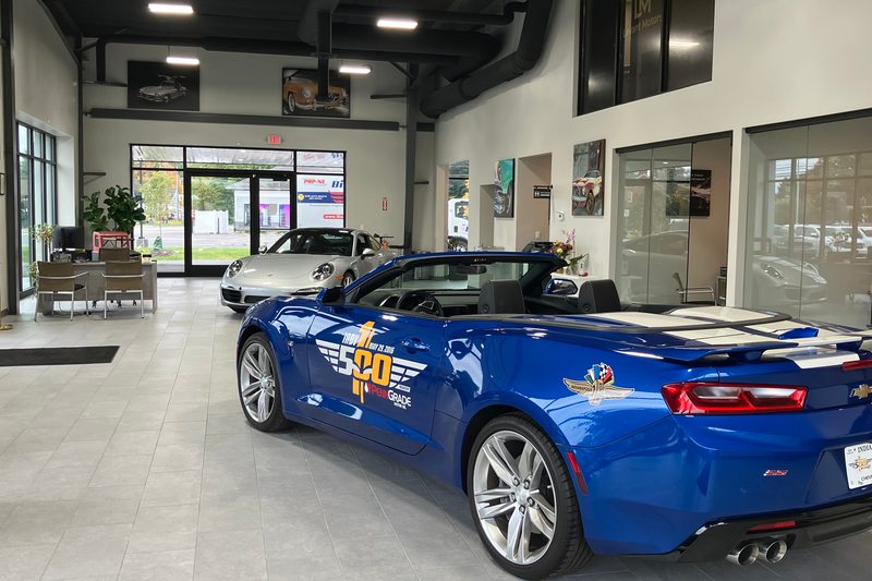 The bright Levant Motors showroom with a blue convertible and automotive artwork